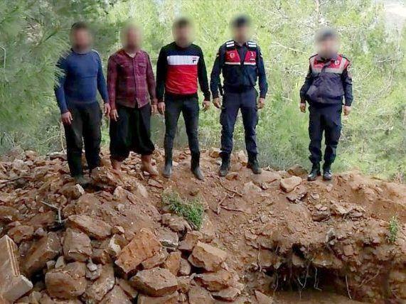 Drei Festgenommene und zwei Beamte der türkischen Jandarma im Wald