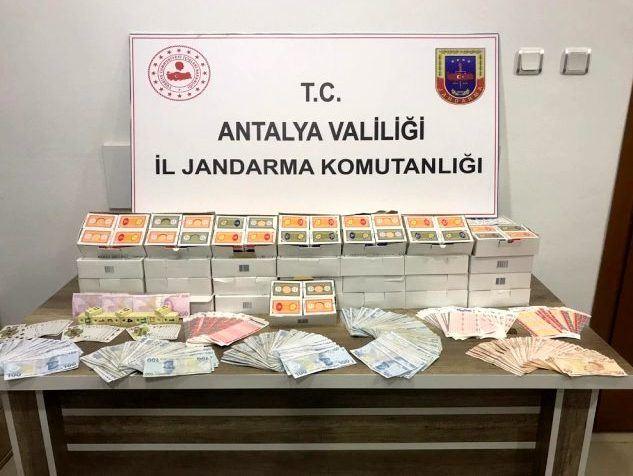 Stapelweise Geldscheine und Spielkarten vor Schild der türkischen Jandarma