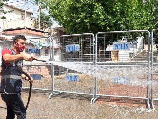 Mann reinigt Strasse vor Polizei-Zaun mit Schlauch