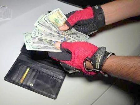 Mann mit Handschuhen zeigt Dollar-Scheine